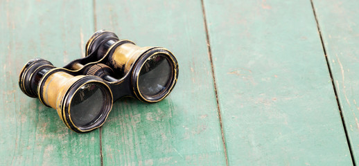 Search concept, old binoculars on a wooden table, web banner with copy space