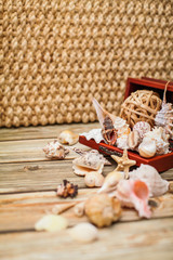 Close up Ancient casket for jewelry with collection of different seashells on wooden table.