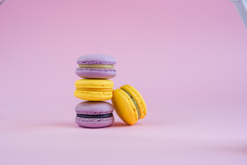 Tasty violet and yellow french macaron cakes on yellow background.