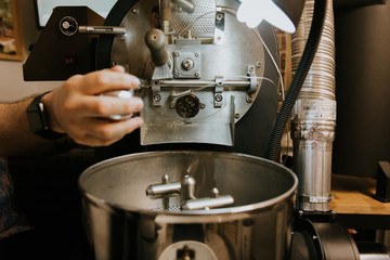 Fresh Roasted Natural Coffee Beans Cascading out of Industrial Coffee Bean Roaster Machine Inside the Coffee Shop