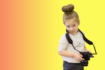 A little clever girl in business dress holds a reflex camera in her hands. The intelligent child learns to take pictures.