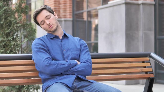oung Man Sleeping while Sitting Outdoor on Bench