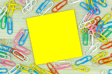 Yellow Note with set of colorful paper clips on wooden background.business creativity concepts