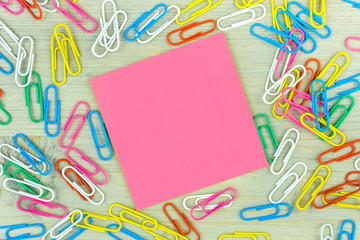 Pink Note with set of colorful paper clips on wooden background.business creativity concepts