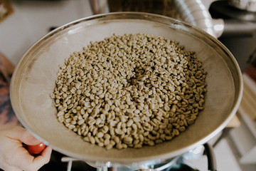 Fresh Green Organic Natural Coffee Beans being Poured into Industrial Coffee Roasting Machine in a Coffee Shop
