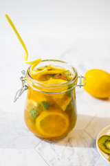 Freshly squeezed orange juice with pulp, kiwi and lemon on a light background. Vertical orientation