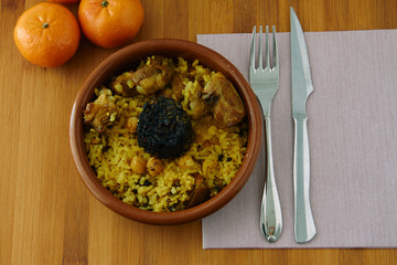 Baked rice in a pottery dish accompanied by pork, chickpeas, blood sausage, tomato and garlic. Traditional 