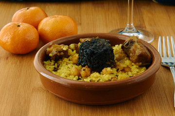 Baked rice in a pottery dish accompanied by pork, chickpeas, blood sausage, tomato and garlic. Traditional 