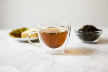 Green tea with jasmine in a transparent mug on a light background. Horizontal orientation
