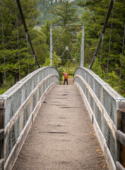 Man Holds up Arms Across Suspension Bridge