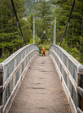 Man Holds up Arms Across Suspension Bridge © kellyvandellen