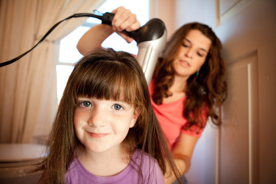 Mother Blowdrying Daughter's Hair at Home
