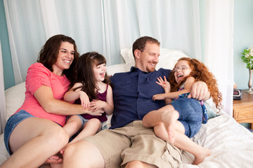 Happy Family Playing on Bed in Bedroom at Home