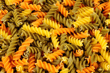 Uncooked tricolore fusilli pasta twist shapes background