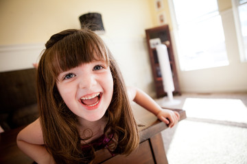 Little Girl Laughing on Table in Living Room at Home