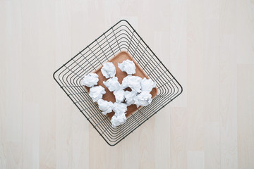 Trash basket and paper crumples. Overflowing waste paper in office garbage bin.