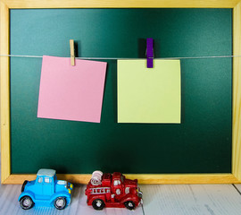 Blank paper clipped with wooden cloth pin against green chalkboard 