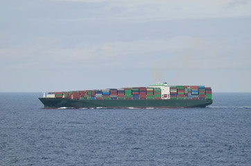 Fully loaded container ship sailing through ocean.