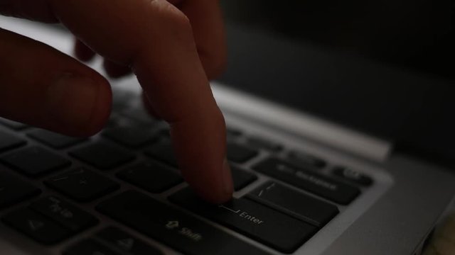 Finger presses the enter button several times on laptop