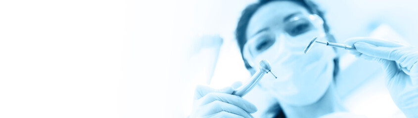 Dentist in mask holding angled mirror and drill
