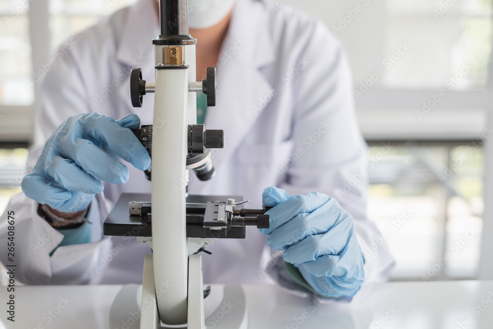 Wall mural a scientist hands working in laboratory with test tube microscope and solutions.