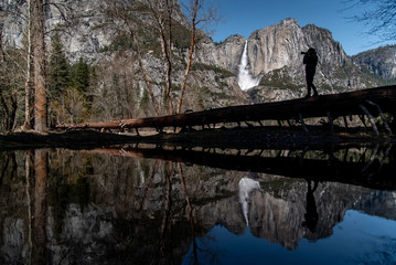 Reflection of Young Asian man photographer and traveler standing on the log enjoy taking photo of...