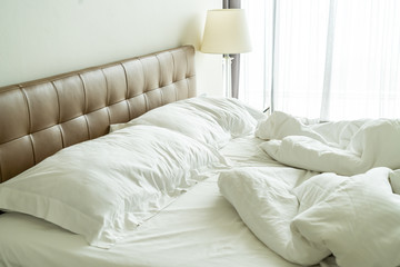 Messy bed with white pillow and blanket on bed