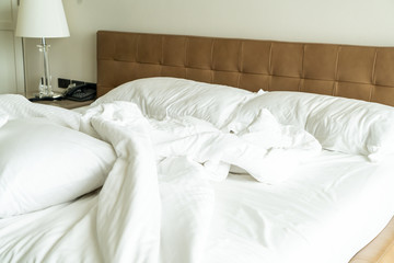 Messy bed with white pillow and blanket on bed