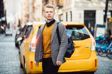 Man walking on city street from the taxi wearing casual outfit with kacjet and backpack in New York City