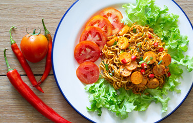 Stir fried spicy yellow noodle with sausage in white dish on gray wooden table