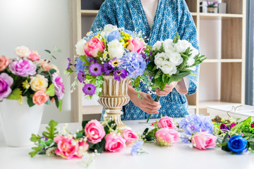 young women business owner florist making or Arranging Artificial flowers vest in her shop, craft and hand made concept