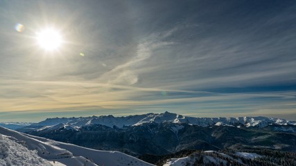 Fototapeta na wymiar Bright sun over the Caucasus mountains covered by snow in the ski resort of Krasnaya Polyana, Russia.