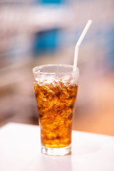 A glass of cola with ice on white table