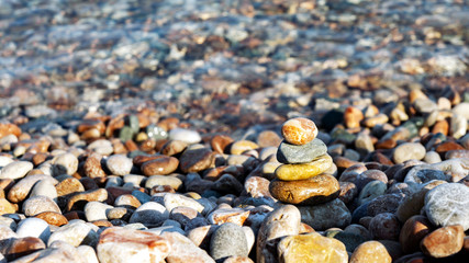 pyramid of stones on the colorful cover of pebbles on the beach with crystal clear water