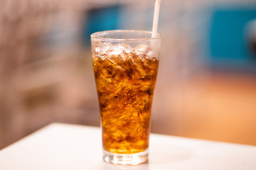 A glass of cola with ice on white table
