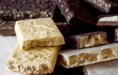 Turron. Traditional Spanish Christmas candy. Torrone and nougat with nuts. Selective focus. Blurred background. Texture, layers.