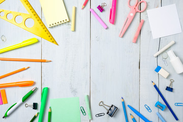 School supplies stationery, color pencils, paints, paper on pastel blue wooden table, back to school background concept with free copy space for text, modern elementary education. Kids desk top view.