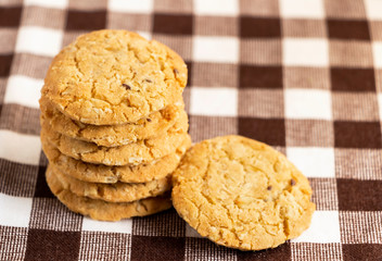 Homemade oatmeal cookies stacked on the brown cloth. Its are a nutrient-rich food associated with protein and fiber.