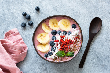 Acai vegan smoothie coconut bowl topped with banana, blueberry, goji berries and linseeds. Table...