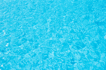 Swimming pool blue water surface with bright sun light reflection.