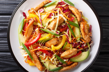 Delicious coleslaw salad with chicken, avocado and vegetables close-up on a plate. horizontal top view
