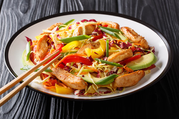 Colorful healthy asian cabbage salad with chicken, avocado and vegetables close-up on a plate. horizontal