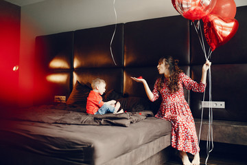 Pregnant woman at home. Mother with son in a bed. Family in a room with decorstions for Valentine's day