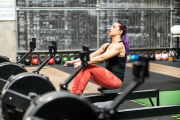 Fototapeta na wymiar Young woman working out on a rowing machine