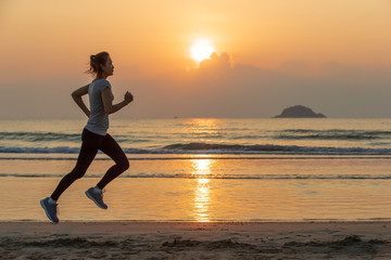 Plakat Woman running on beach at sunrise