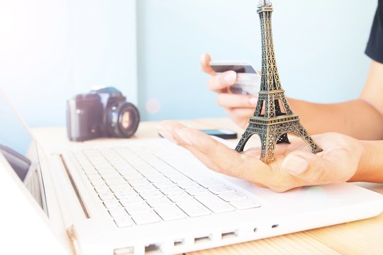 Hands holding eiffel tower model and credit card. Woman using laptop computer and booking hotel. Travel Paris, Pray for Paris