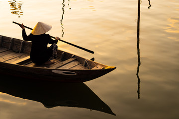 Vietnamese woman in traditional bamboo hat rowing
