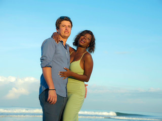  happy and romantic mixed race couple with attractive black African American woman and Caucasian man playing on beach having fun enjoying holidays in multiracial love