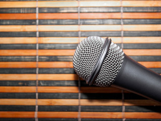 Top-Down View of A Microphone Head and Silver Grille on A Striped Yellow and Black Bamboo Mat...