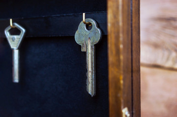 Keys Hanging on Golden Hooks in a Wall Key Holder on Rustic Wooden Background. Mortgage, Insurance, Security Concept.